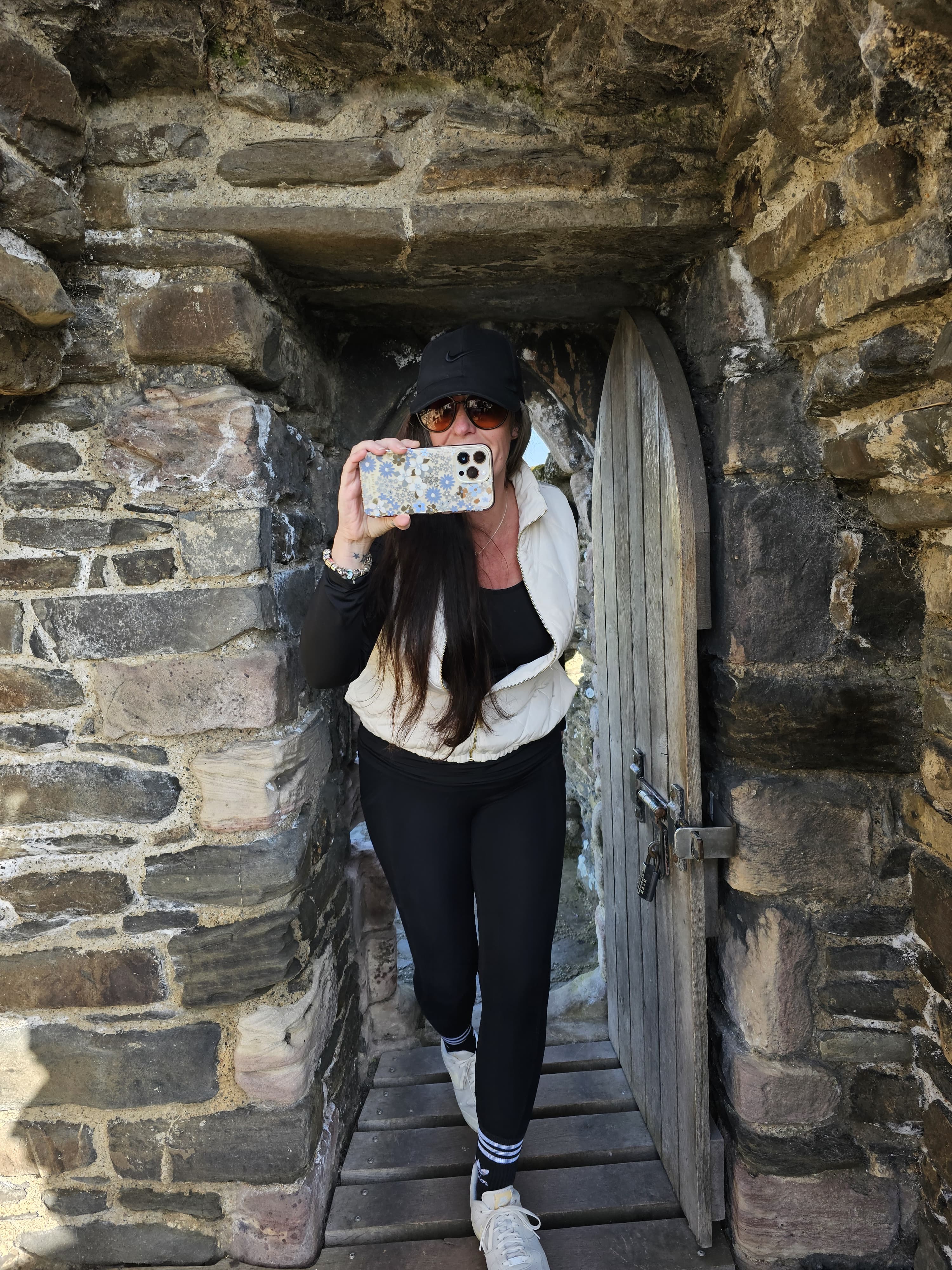Jennifer David Taking a photo with her cell phone in an old brick doorway
